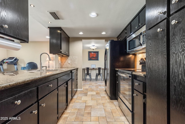 kitchen with a sink, visible vents, appliances with stainless steel finishes, tasteful backsplash, and stone finish floor