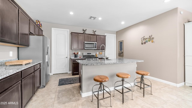 37820 W San Sisto Ave, Maricopa, AZ 85138 - kitchen featuring light stone counters, a sink, dark brown cabinetry, stainless steel appliances, and visible vents