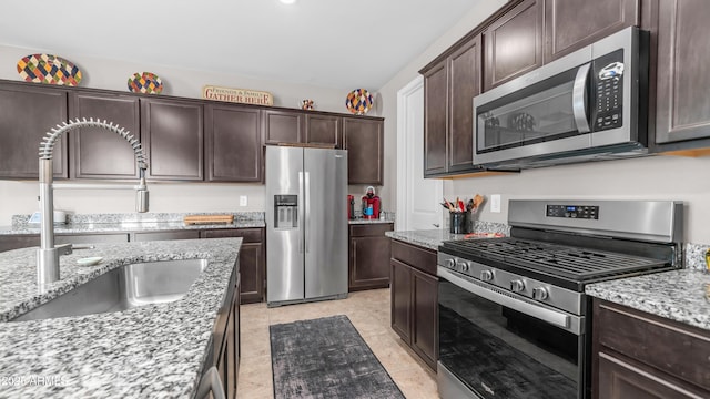 37820 W San Sisto Ave, Maricopa, AZ 85138 - kitchen with light stone counters, dark brown cabinetry, stainless steel appliances, and a sink