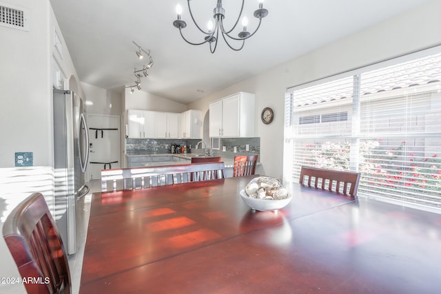 dining room with a notable chandelier, concrete floors, lofted ceiling, and sink