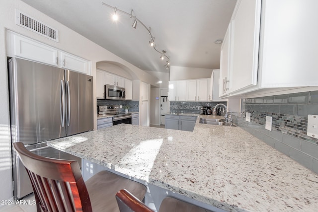 kitchen featuring stainless steel appliances, white cabinets, and a kitchen bar