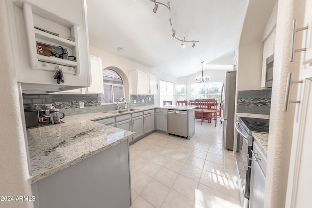 kitchen with hanging light fixtures, lofted ceiling, white cabinets, appliances with stainless steel finishes, and sink