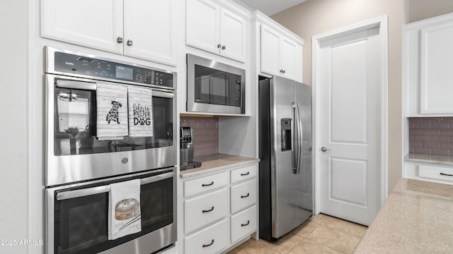 kitchen with white cabinetry, light tile patterned floors, stainless steel appliances, and backsplash