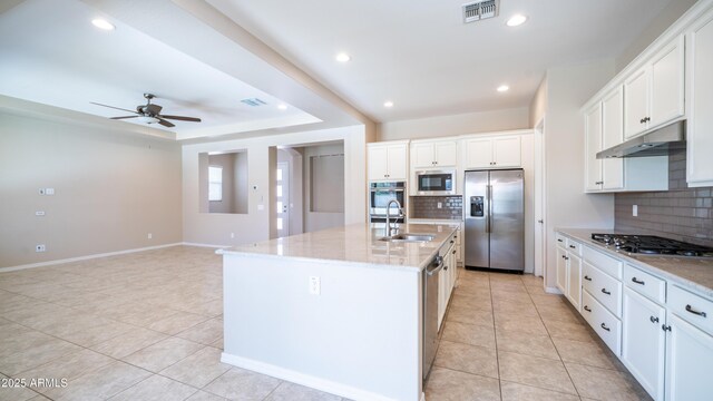 kitchen with stainless steel appliances, under cabinet range hood, a sink, visible vents, and light tile patterned flooring