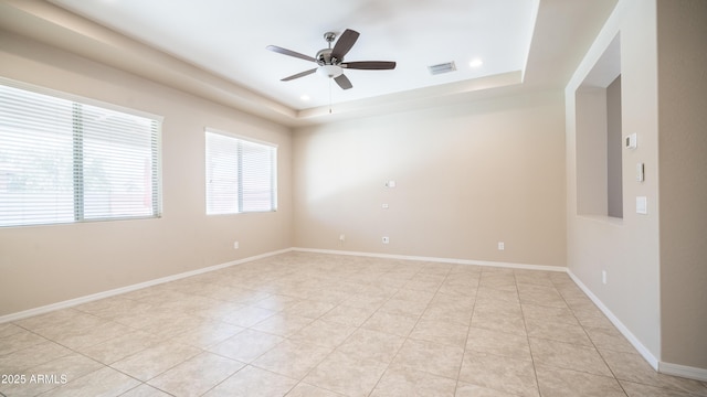 empty room featuring visible vents, a raised ceiling, ceiling fan, and light tile patterned flooring