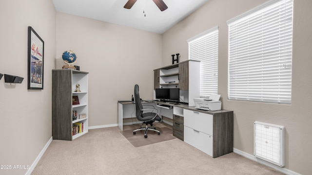 office featuring a ceiling fan, light colored carpet, and baseboards