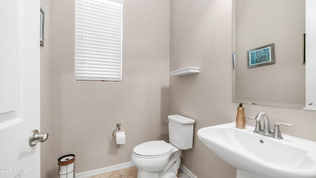 bathroom featuring baseboards, toilet, tile patterned flooring, and a sink