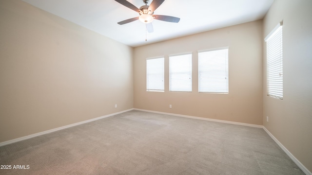 empty room featuring ceiling fan, light colored carpet, and baseboards
