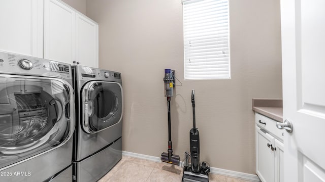 laundry area with light tile patterned floors, cabinet space, washing machine and clothes dryer, and baseboards