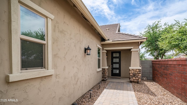 property entrance with fence and stucco siding