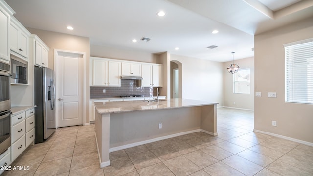 kitchen featuring tasteful backsplash, arched walkways, light tile patterned floors, stainless steel fridge, and visible vents