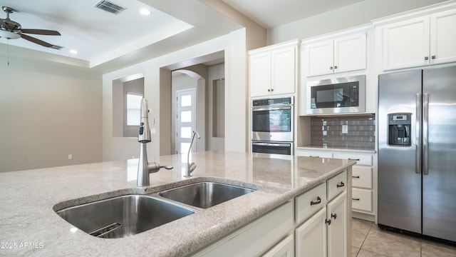 kitchen with stainless steel appliances, white cabinets, a sink, visible vents, and a ceiling fan
