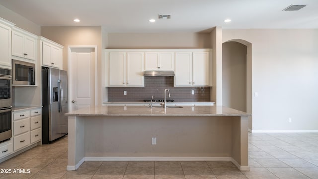 kitchen with decorative backsplash, a sink, visible vents, stainless steel appliances, and arched walkways