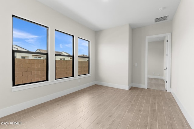 unfurnished room with light wood-type flooring, visible vents, and baseboards