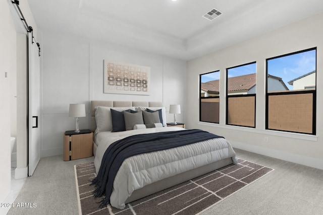 carpeted bedroom with a barn door, visible vents, and baseboards