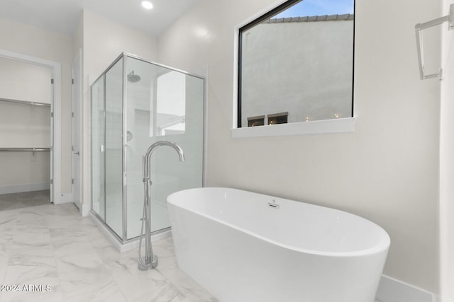 full bath featuring a stall shower, baseboards, a soaking tub, marble finish floor, and a spacious closet