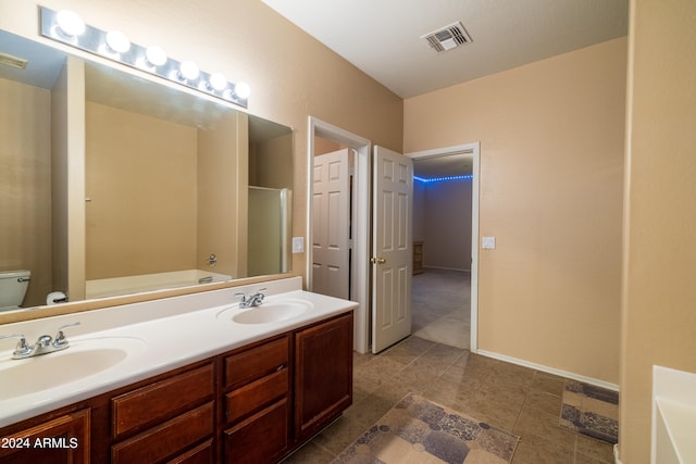 bathroom with a tub to relax in, vanity, toilet, and tile patterned floors