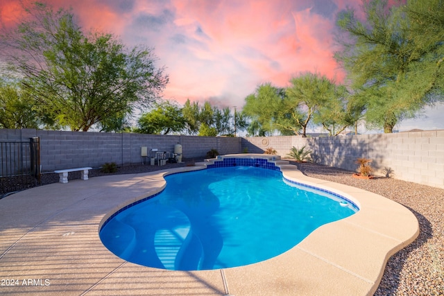 pool at dusk featuring a patio area