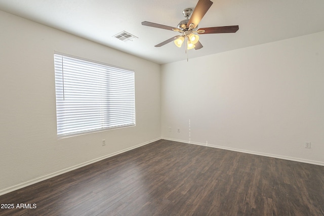 unfurnished room featuring dark wood finished floors, visible vents, and baseboards