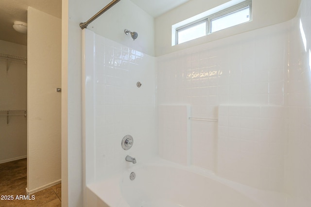 bathroom with shower / tub combination, a walk in closet, and tile patterned floors