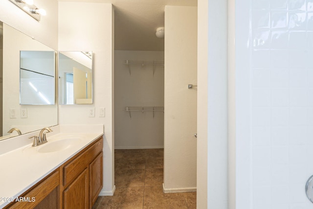 bathroom featuring a spacious closet, tile patterned flooring, vanity, and baseboards