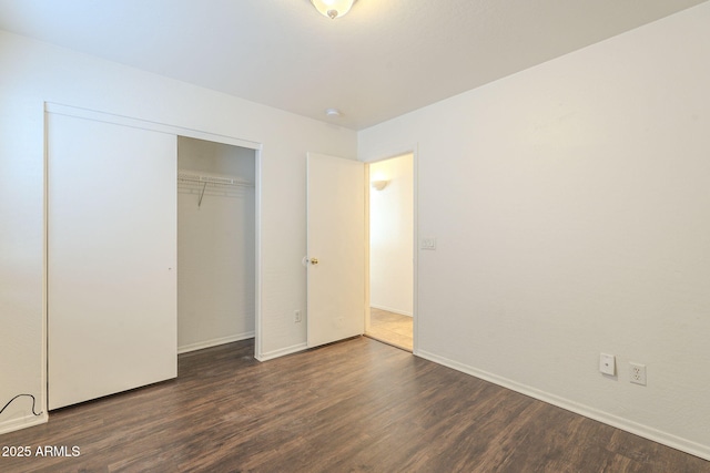 unfurnished bedroom with a closet, baseboards, and wood finished floors