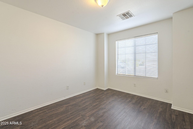 unfurnished room featuring dark wood-style floors, visible vents, and baseboards