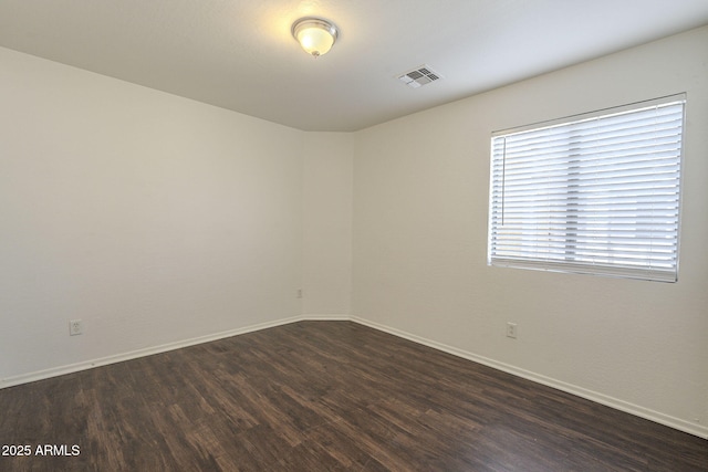 unfurnished room featuring baseboards, visible vents, and dark wood-style flooring