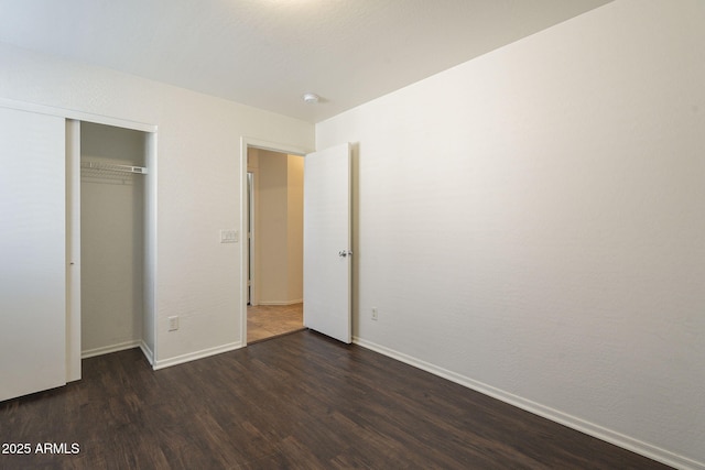 unfurnished bedroom featuring a closet, baseboards, and dark wood-type flooring