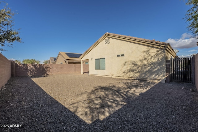 back of house featuring a tile roof, a fenced backyard, and stucco siding