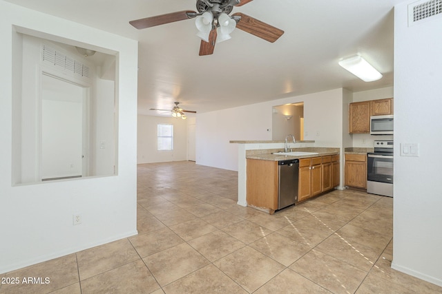 kitchen with stainless steel appliances, light countertops, visible vents, a sink, and a peninsula