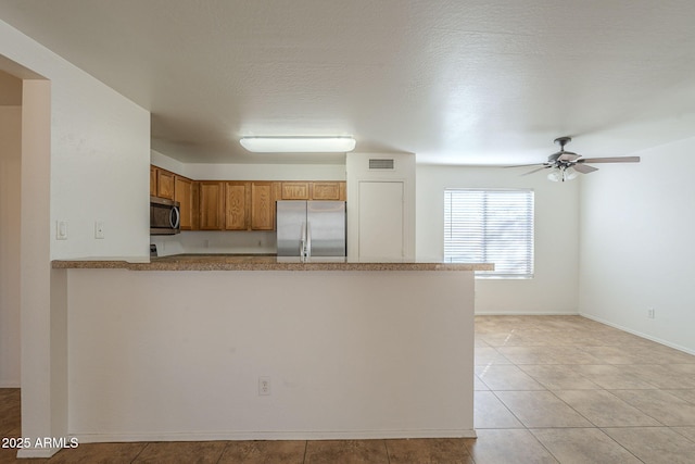 kitchen featuring brown cabinets, visible vents, appliances with stainless steel finishes, ceiling fan, and a peninsula