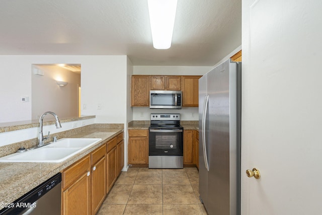 kitchen featuring light tile patterned floors, brown cabinets, stainless steel appliances, light countertops, and a sink