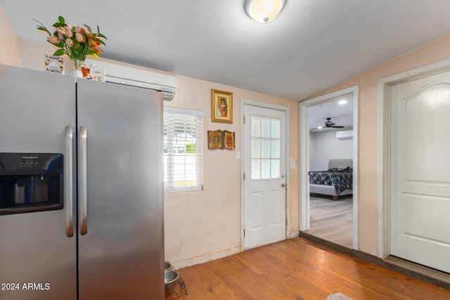 kitchen with light hardwood / wood-style floors, ceiling fan, a wall mounted AC, lofted ceiling, and stainless steel fridge