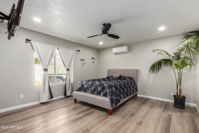 bedroom featuring an AC wall unit, ceiling fan, and light hardwood / wood-style flooring