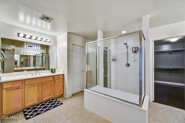 bathroom with vanity, a textured ceiling, tile patterned floors, and a shower with door