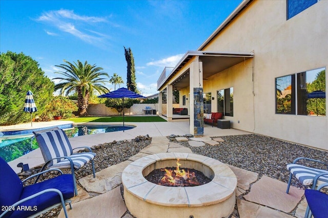 view of patio / terrace with a fenced in pool, central AC unit, and an outdoor fire pit