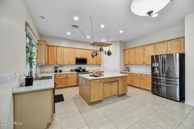 kitchen featuring appliances with stainless steel finishes, sink, light tile patterned floors, light brown cabinets, and a kitchen island