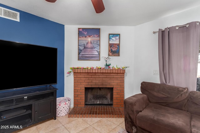 living area featuring a ceiling fan, visible vents, a fireplace, and light tile patterned floors