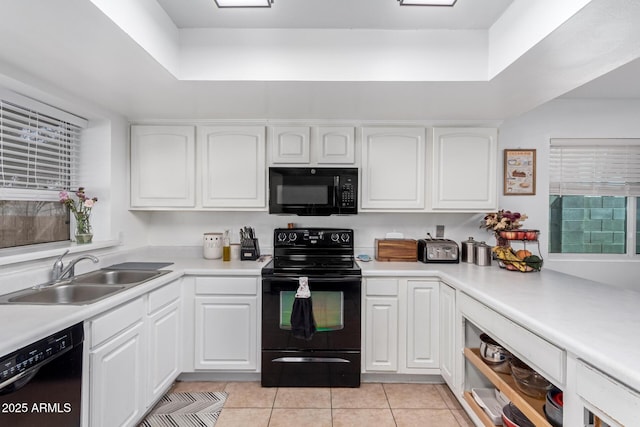 kitchen with light tile patterned floors, light countertops, white cabinetry, a sink, and black appliances