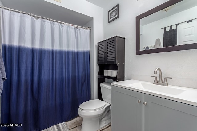 full bath featuring a textured wall, a shower with shower curtain, vanity, and toilet