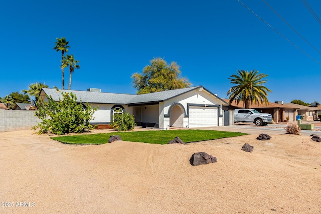 single story home with driveway, an attached garage, and fence