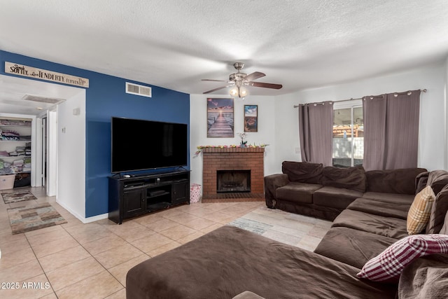 living room featuring a textured ceiling, light tile patterned flooring, a fireplace, and visible vents