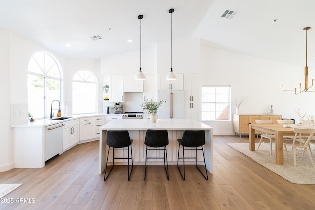 kitchen with light wood finished floors, white appliances, a sink, and visible vents