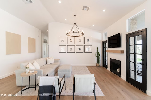 living area with recessed lighting, a fireplace, visible vents, vaulted ceiling, and light wood-type flooring