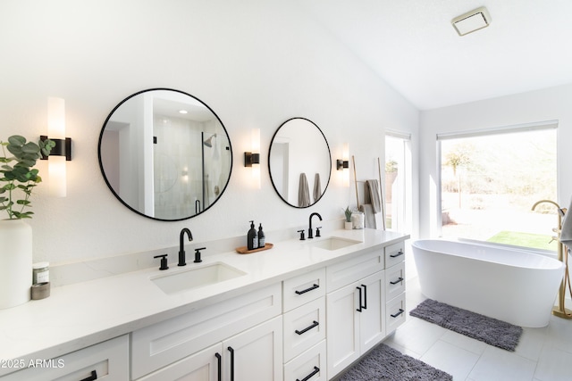 bathroom featuring a stall shower, lofted ceiling, a sink, and double vanity