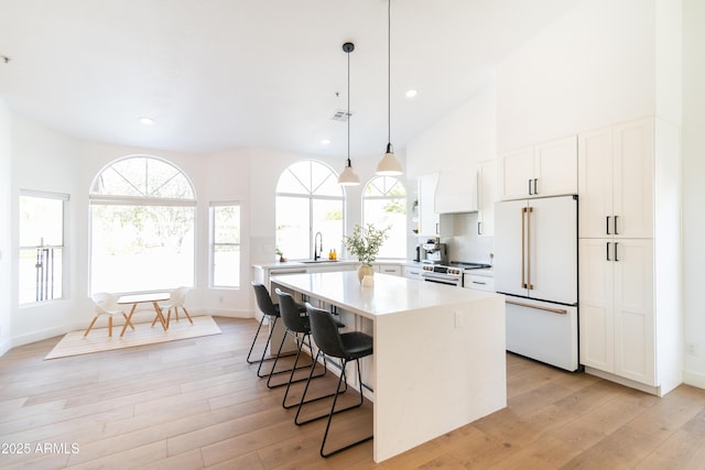 kitchen with white appliances, a kitchen island, a kitchen breakfast bar, light countertops, and light wood-type flooring