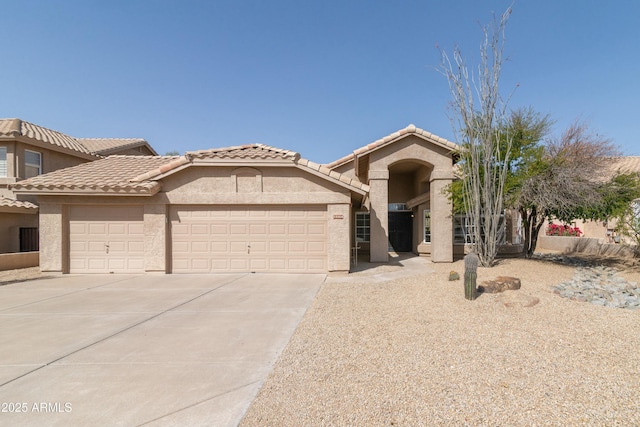 mediterranean / spanish house with driveway, a tiled roof, an attached garage, and stucco siding