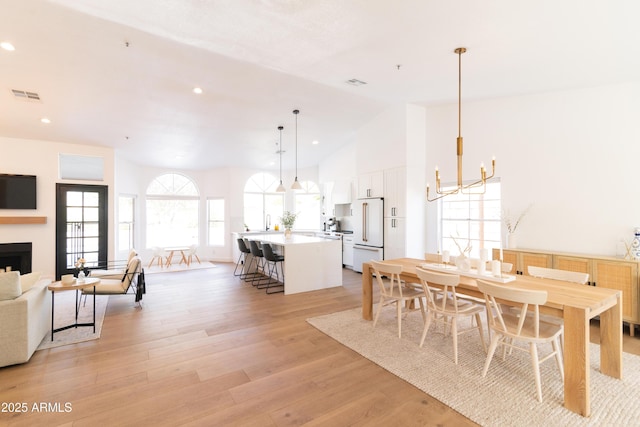 dining space with high vaulted ceiling, light wood-style flooring, recessed lighting, visible vents, and an inviting chandelier