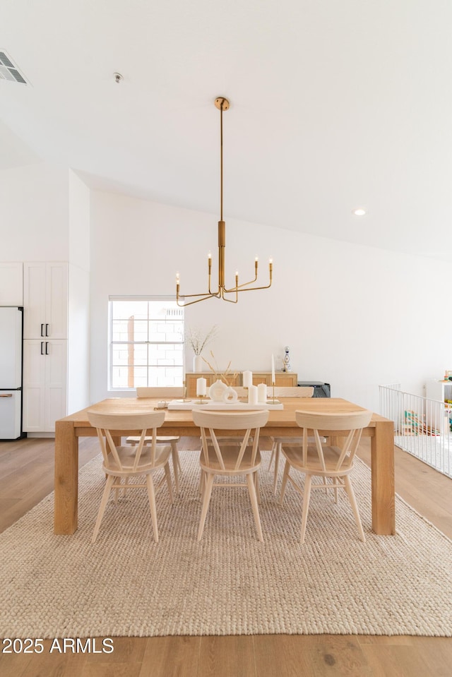 dining space with lofted ceiling, recessed lighting, visible vents, light wood-style flooring, and an inviting chandelier